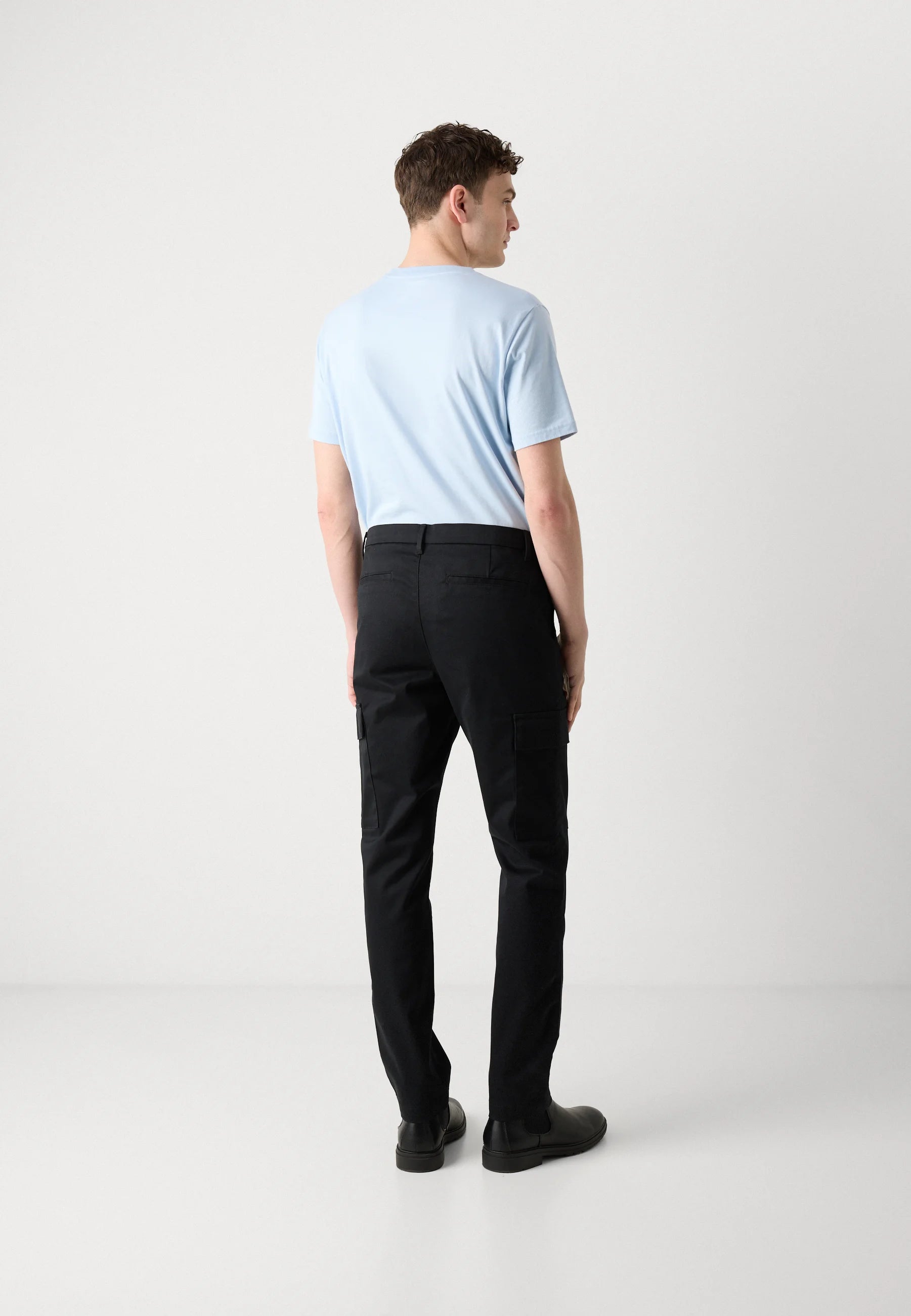 Man wearing a light blue shirt and black cargo pants no fade