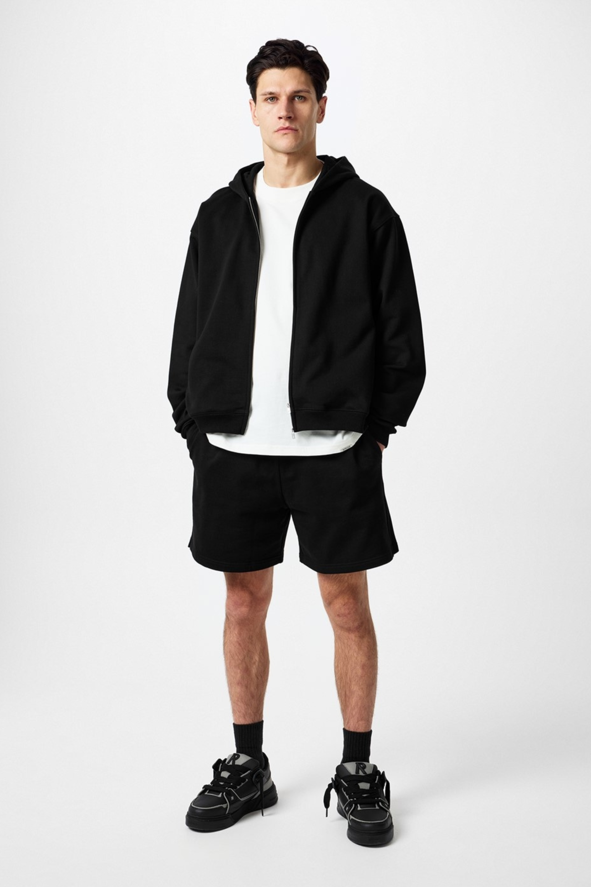 Man in black hoodie, shorts, white t-shirt, and sneakers.