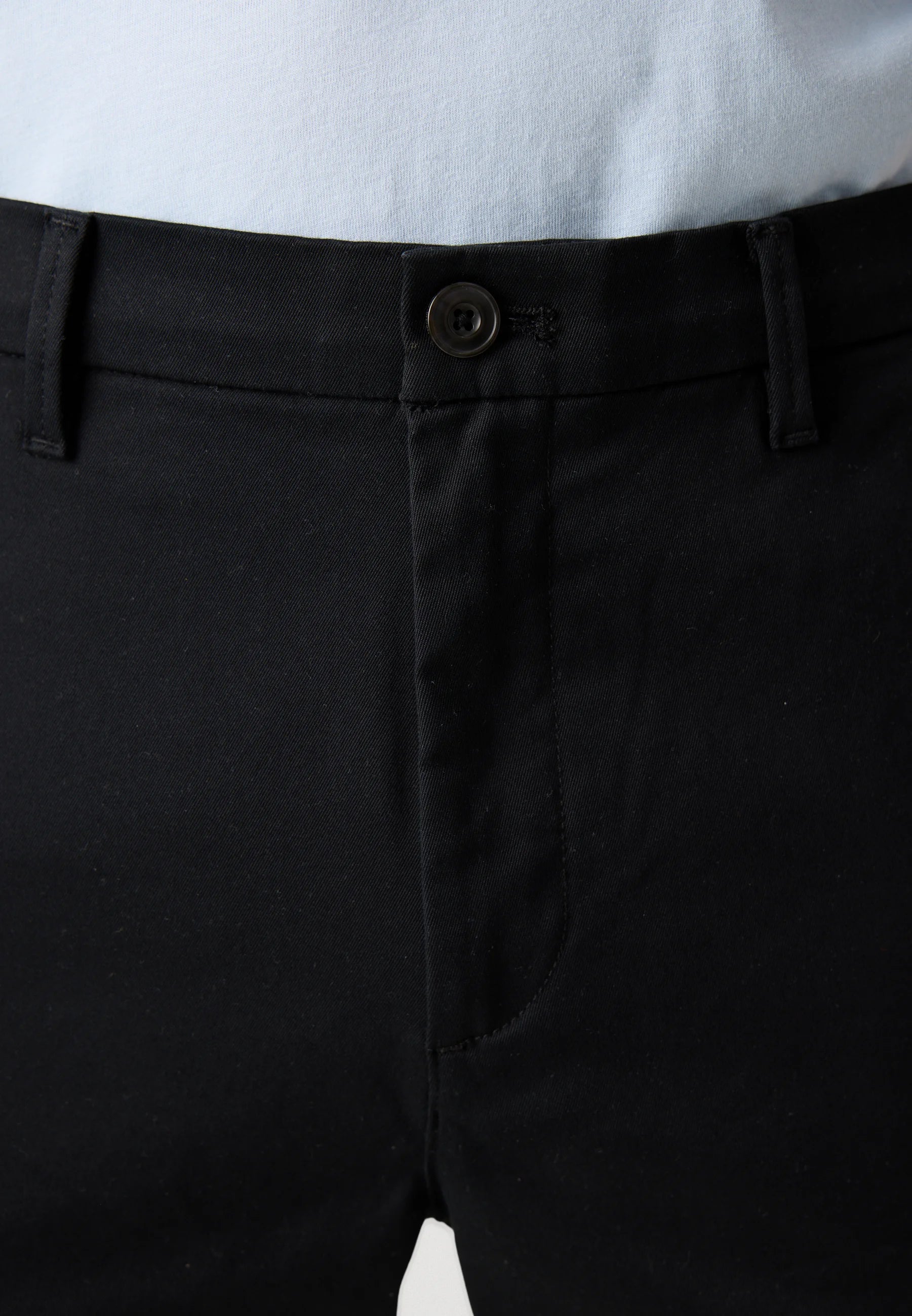 Close-up of black cargo pants with a button on a white background