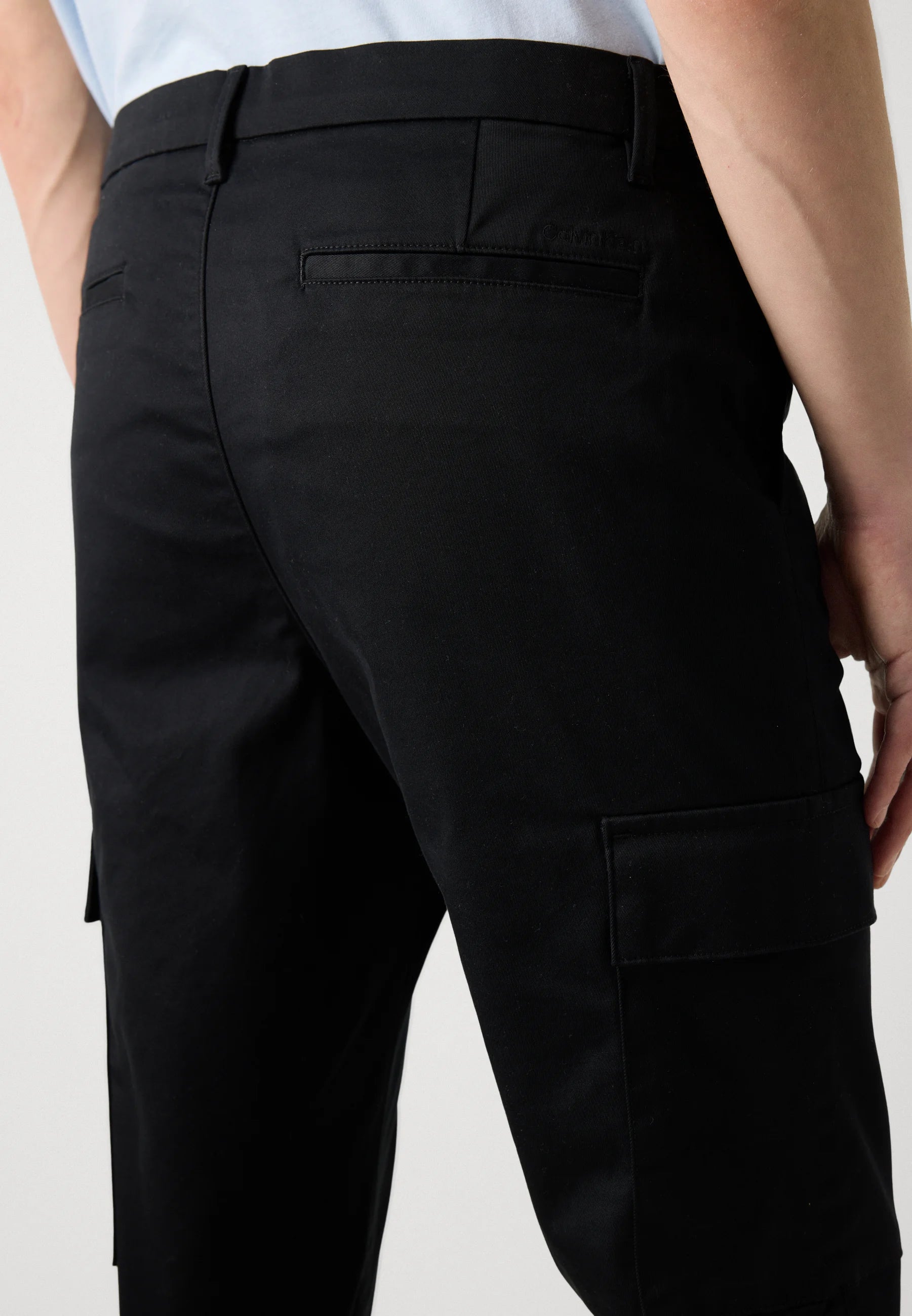 Black cargo pants worn by a person on a white background