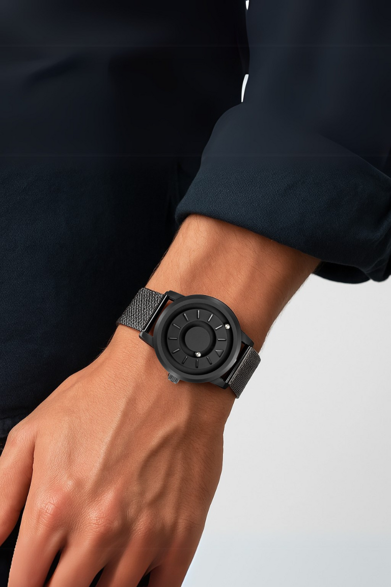 Black wristwatch on a person's wrist with a plain background