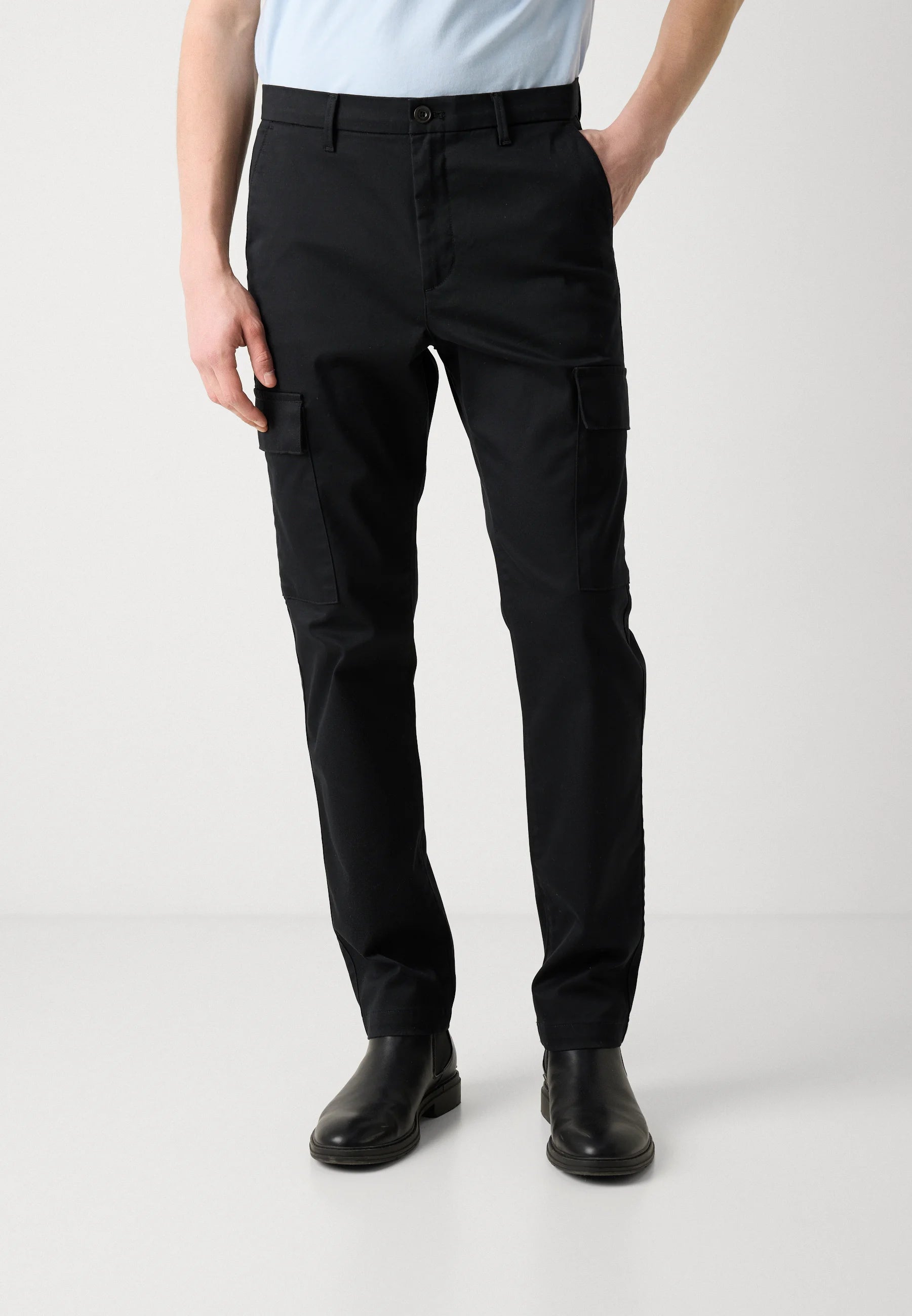 Person wearing black cargo pants on a white background