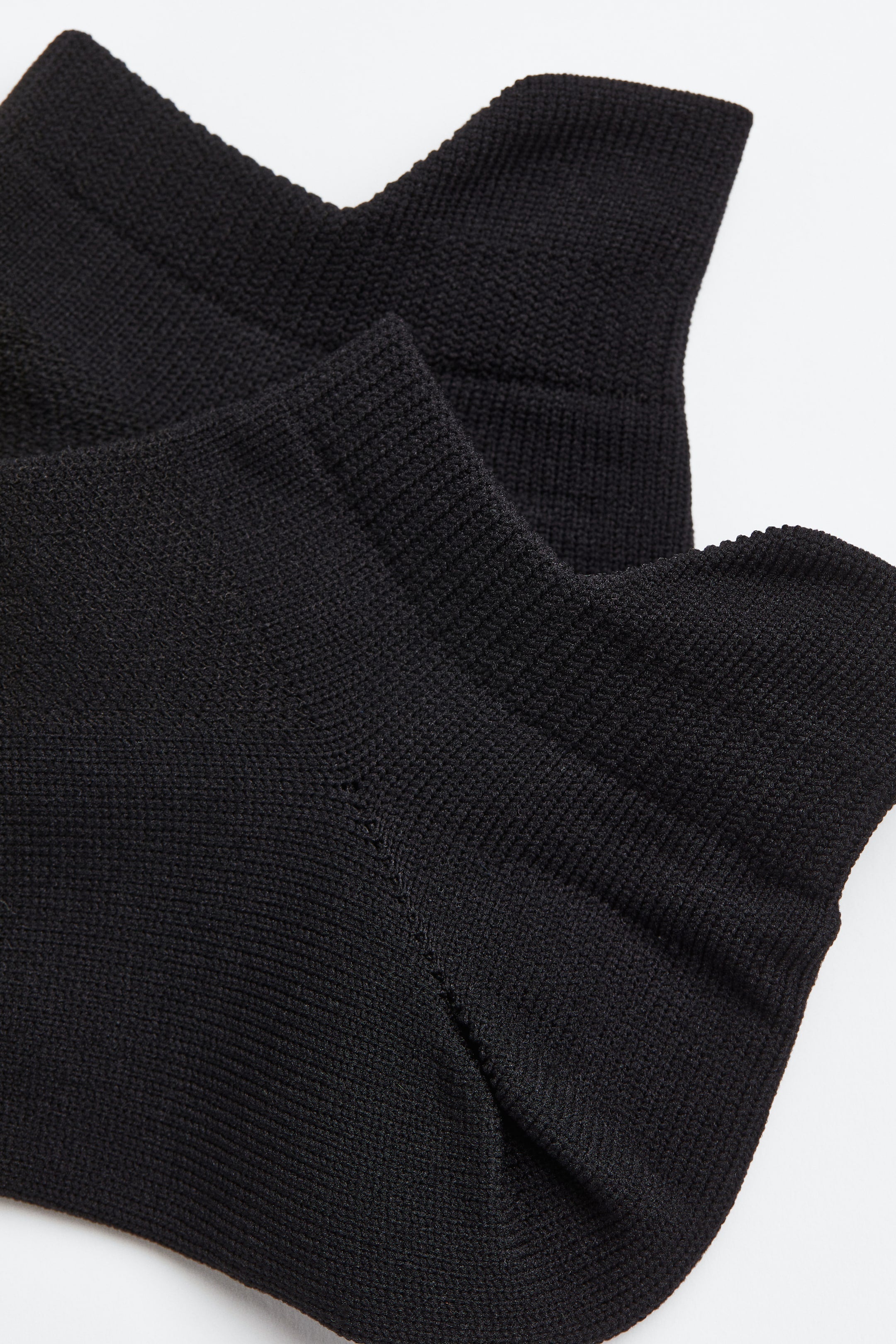 Close up view of two black knit socks.