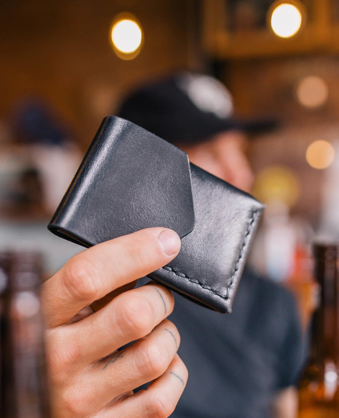 Person holding a black leather wallet with a blurred background
